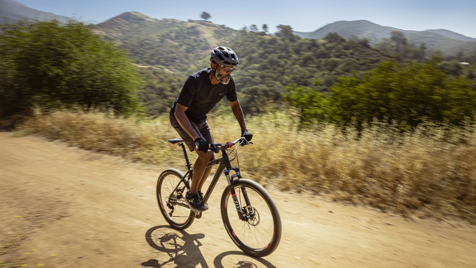 lifestyle image of a man on his bicycle riding through rolling hills